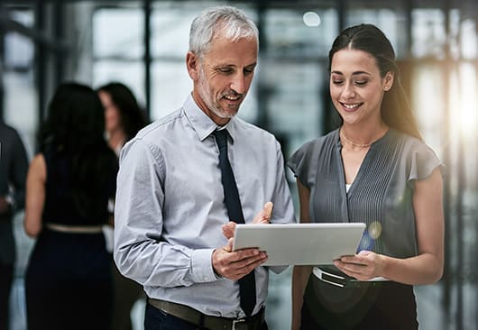 An image of a male and female professional standing and reviewing a paper