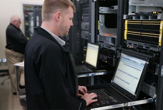 Engineers Study on Laptops in Server Room