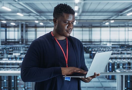 Engineer in Data Center Room on Laptop