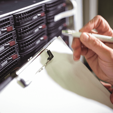 Close Up of Clipboard and Hand Holding Pen in Data Center