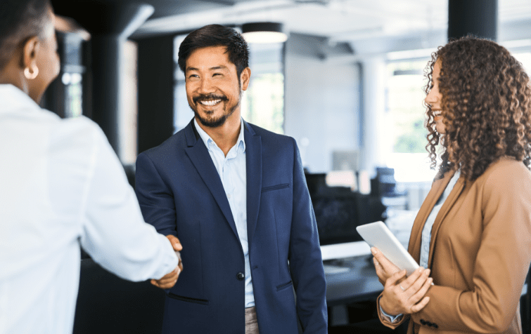 Man in navy suit shaking hands with a woman.