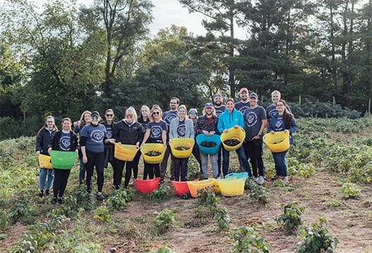 A group photo of Service Express employees with baskets full of vegetables for the KFB farm