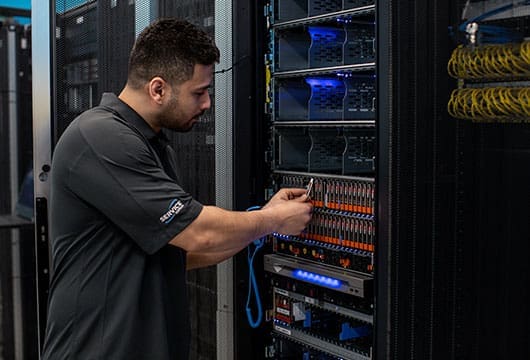 An image of a male Service Express engineer replacing parts in an equipment rack
