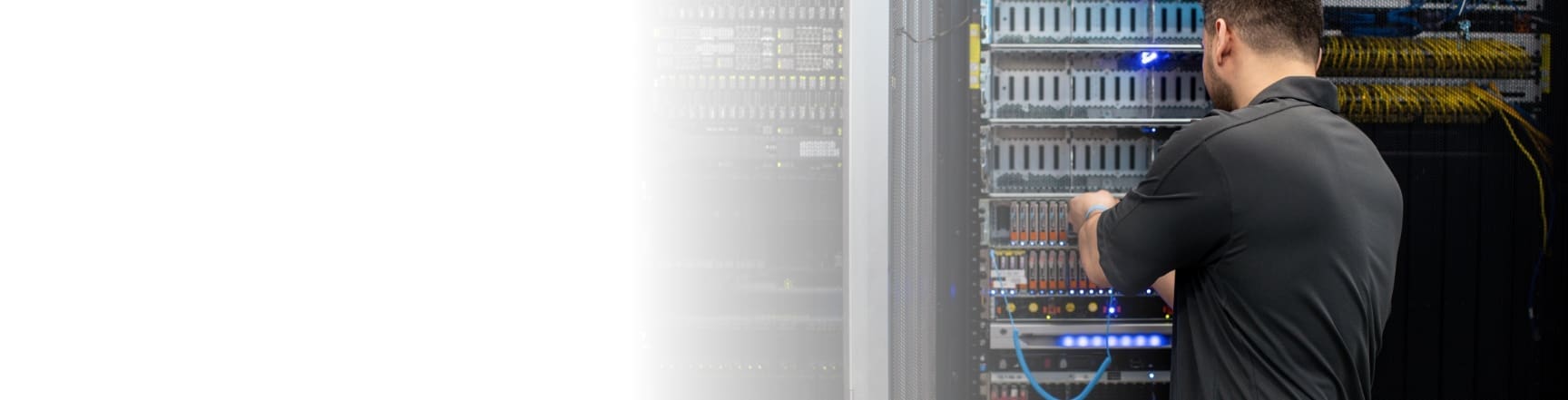 An image of an engineer plugging cables into equipment in a rack