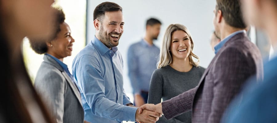 coworkers gathered smiling and shaking hands