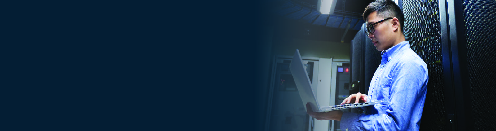 An image of an engineer in a data center holding a laptop