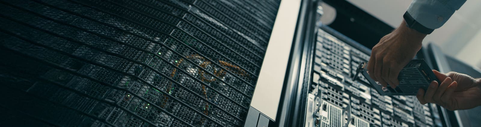 An image from below two hands holding a part in front of an equipment rack