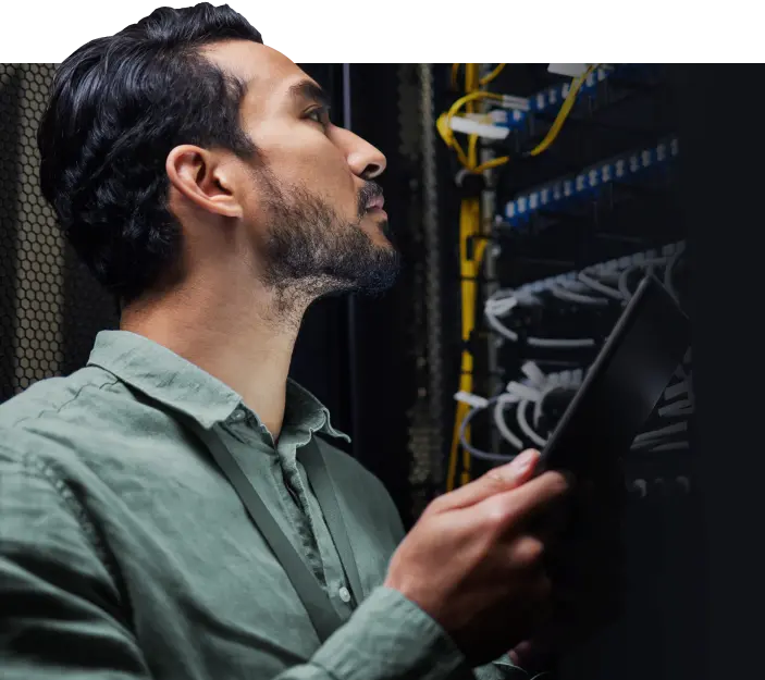 Male engineer in a data center holding tablet inspecting equipment