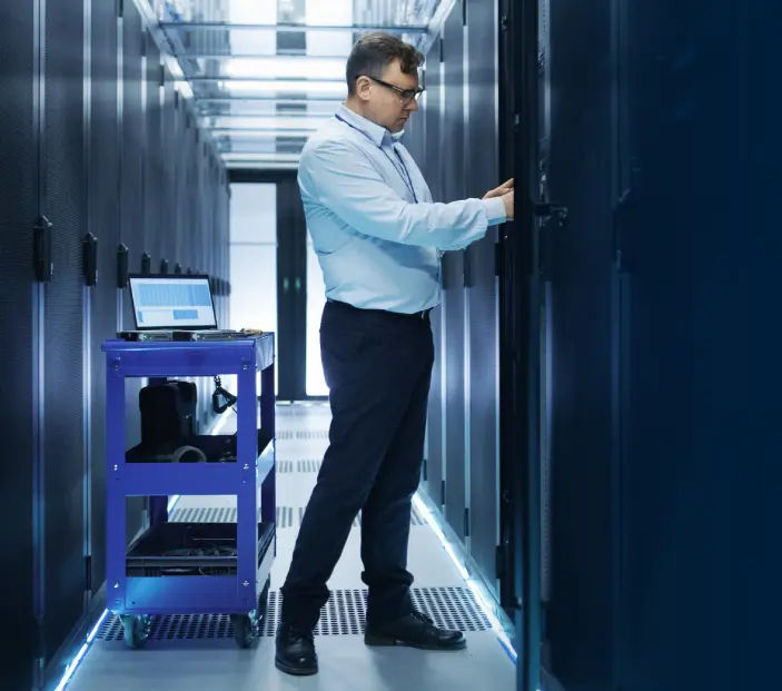 Engineer with cart reaching into equipment rack in a data center