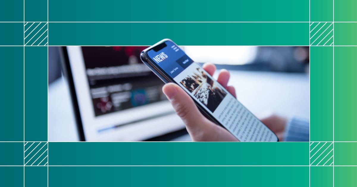 An image of a hand holding a cell phone displaying a news website