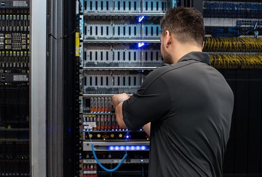 An image of an engineer inspecting equipment in a data center rack