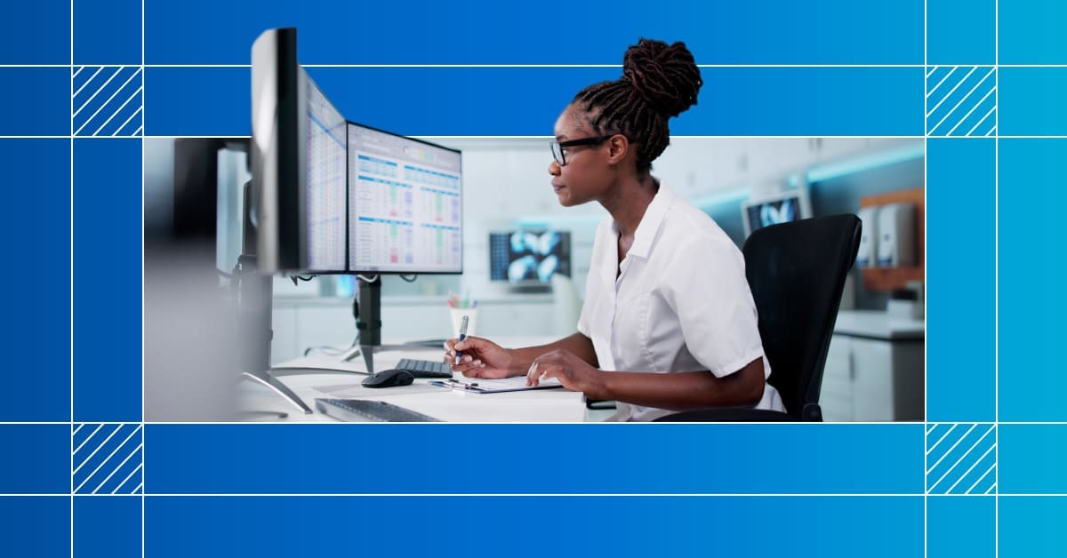 An image of a healthcare worker in front of a computer at a desk making notes