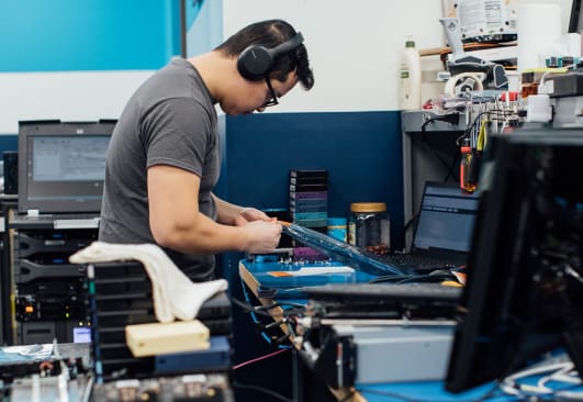 An image of a male engineer wearing headphones fixing equipment