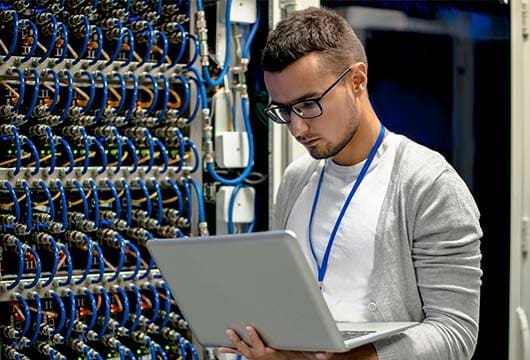 Engineer on Laptop Fixing Network Equipment
