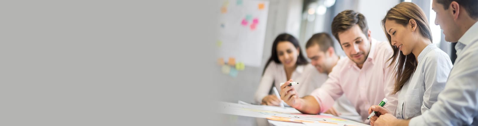 An image of collaborating professionals reviewing a paper with markers in hand
