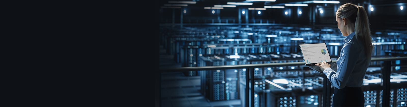 Engineer Overlooking Data Center Holding Laptop with Stats