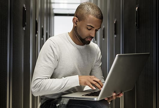 Man working on a laptop in a data centre