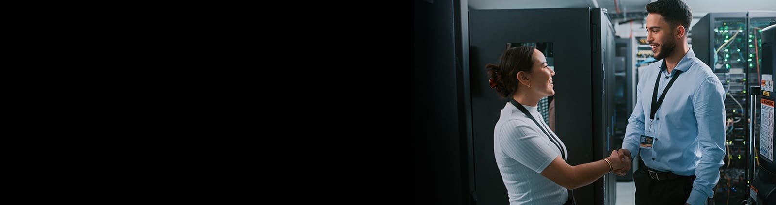 Female and male shaking hands while smiling in a data center
