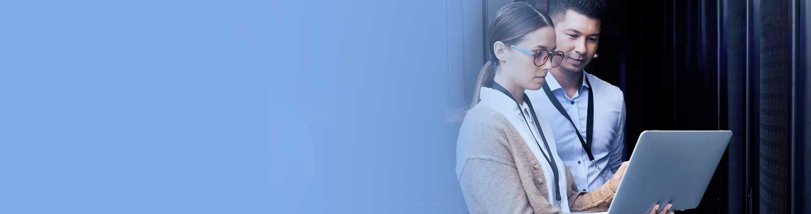 Female wearing glasses and male gazing at laptop