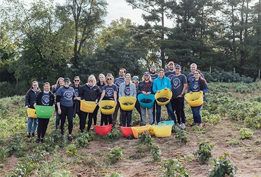 A group photo of Service Express employees with baskets full of vegetables for the KFB farm