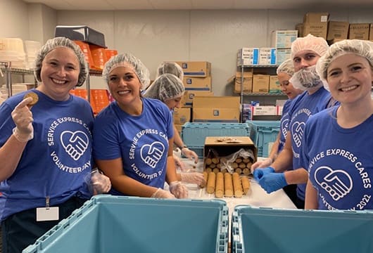 An image of Service Express employees volunteering packing lunches for KFB