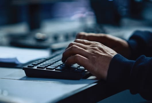 An image of two hands typing at a keyboard