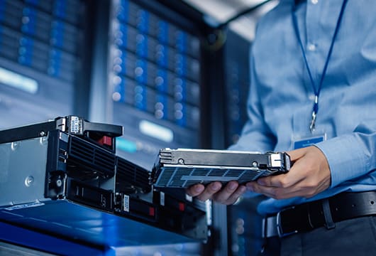 An image of an engineer in a data center replacing a part