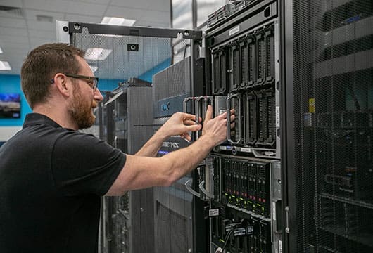 An image of a male engineer in the technical center replacing parts in an equipment rack