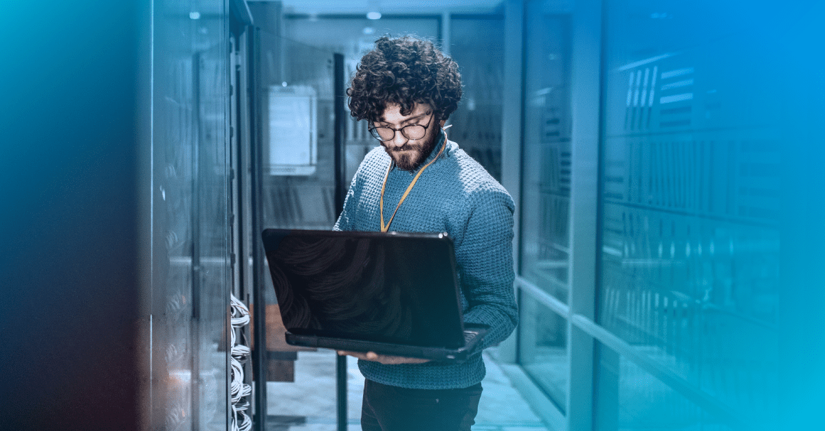 Male standing in data center on a computer with a blue gradient
