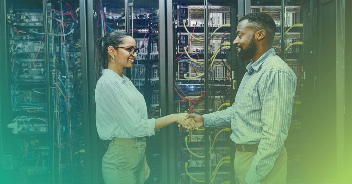 An image of a female and male engineer in a data center shaking hands