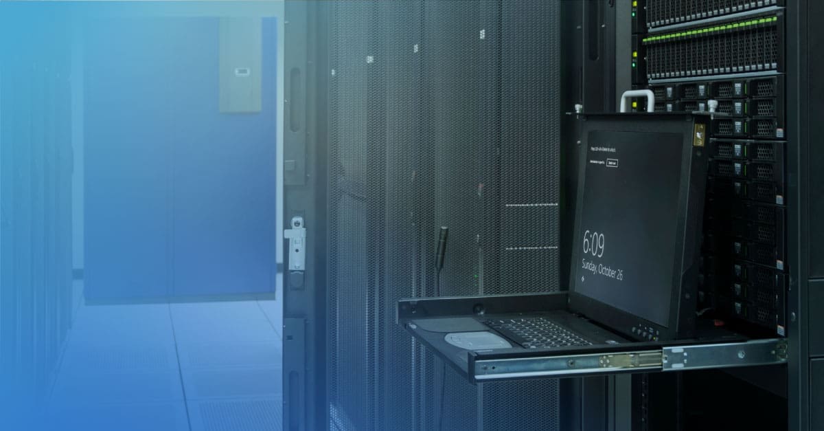 An image of a laptop open in front of an equipment rack