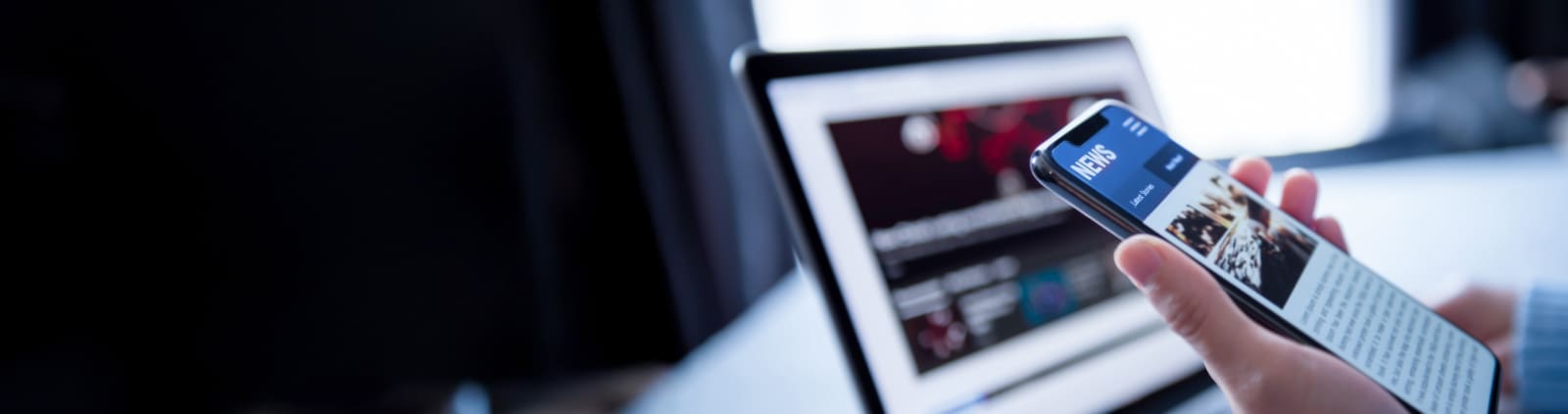 An image of a hand holding a cell phone displaying a news website